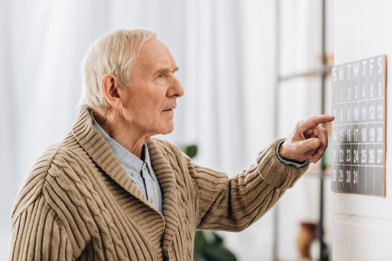 Old man looking at calendar and remembering date