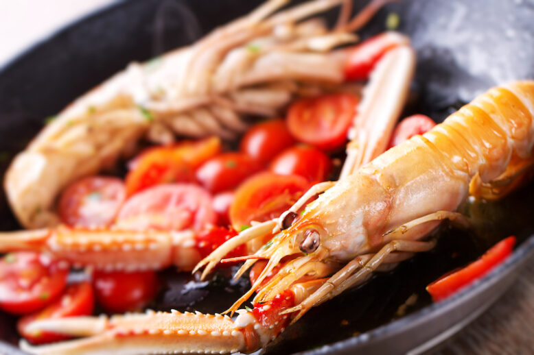 Scampi, preparation and cooking in a pan. Shellfish scampi cooked in a pan with cherry tomatoes.