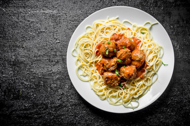 Spaghetti with meat balls on a plate. On black rustic background