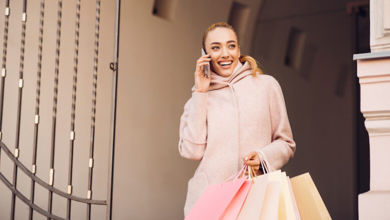 Young woman talking on phone after shopping in boutiques, walking outdoors
