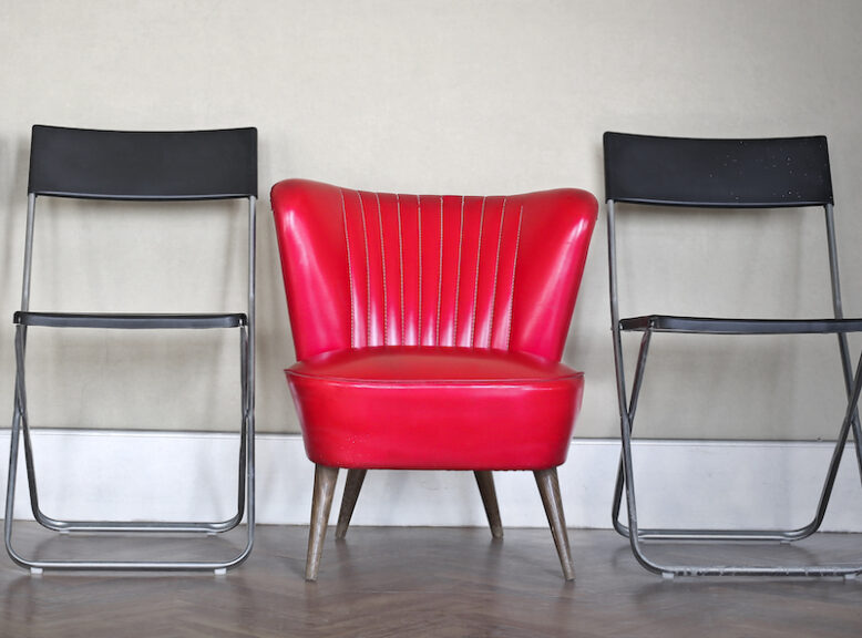 red armchair between two black chairs