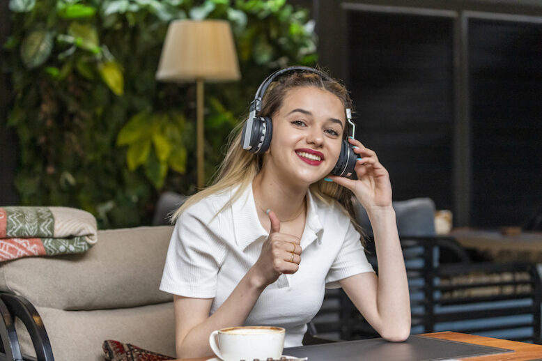 Sweet girl wears headphones and gesture thumb up. High quality photo
