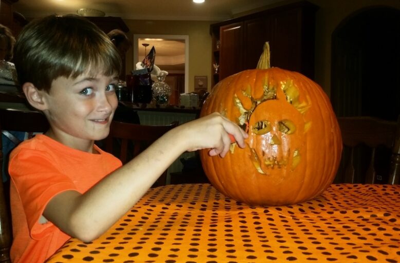 Cheeky young boy curving a pumpking.