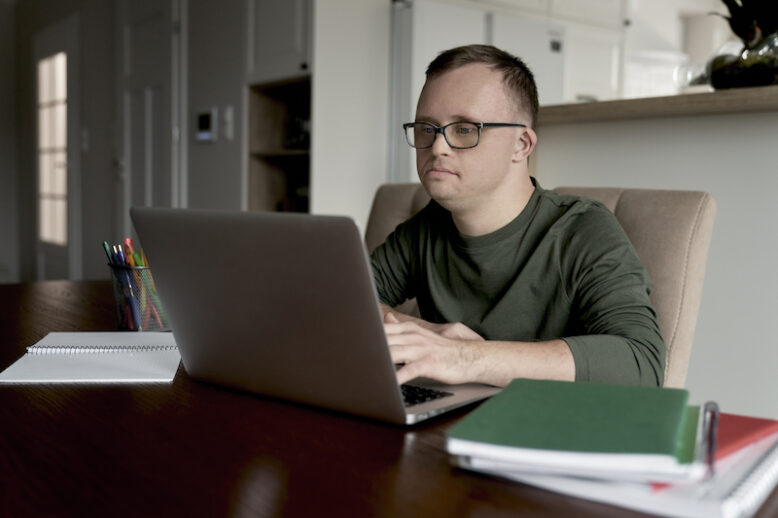 Man with Down syndrome using laptop while studying at home