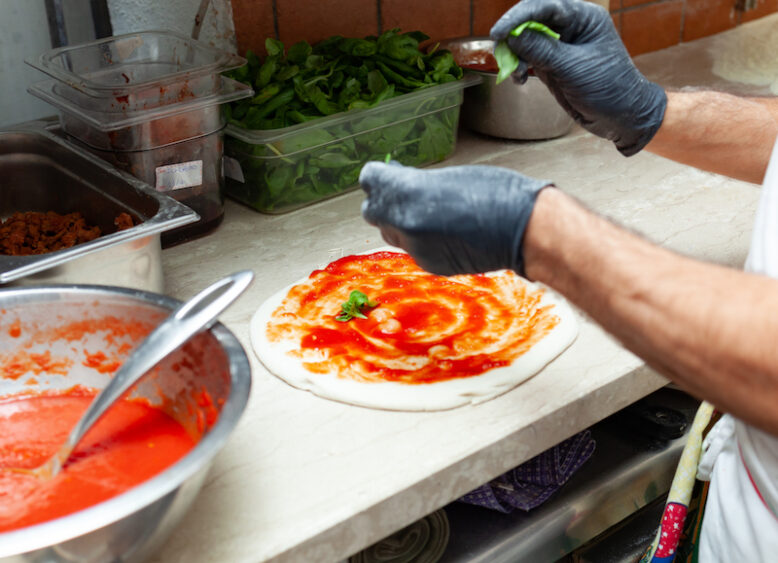 Preparation of traditional Neapolitan pizza with ingredients.