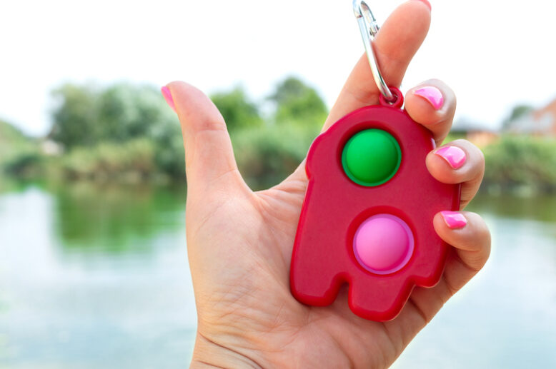 Simple dimple - colorful rubber antistress trinket toy in the hand. Close-up.