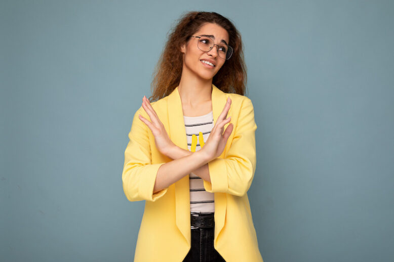 Photo of young woman with sincere emotions wearing stylish yellow jacket.