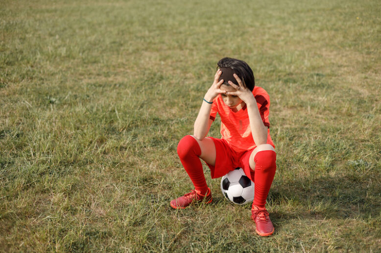 sad girl sitting on soccer ball