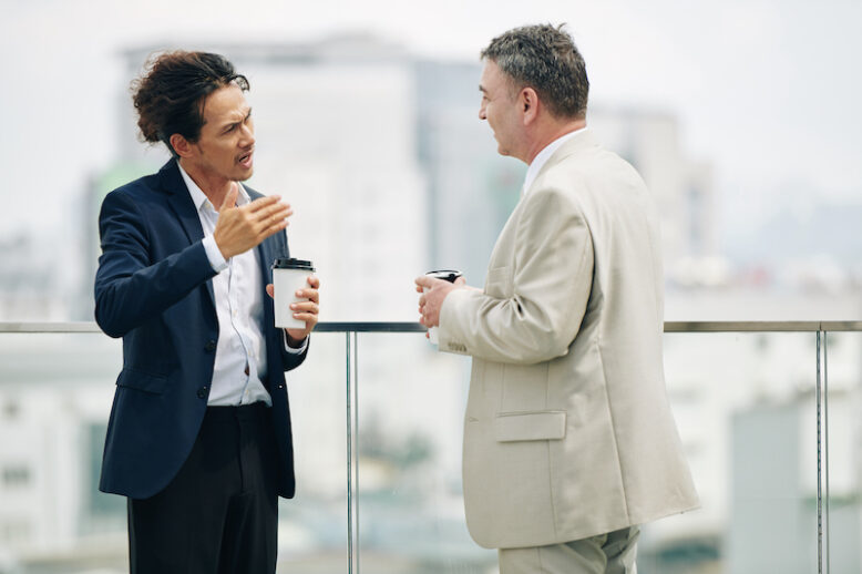 Mixed-race entrepreneur arguing with colleague when they are meeting on rooftop during coffee break