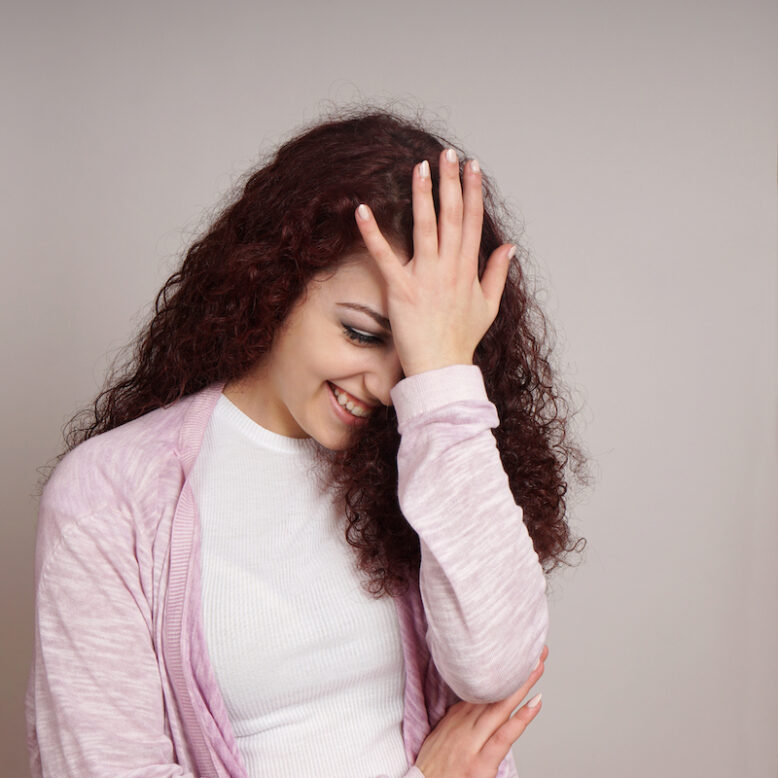 young woman feeling embarrassed with hand on forehead also known as facepalm