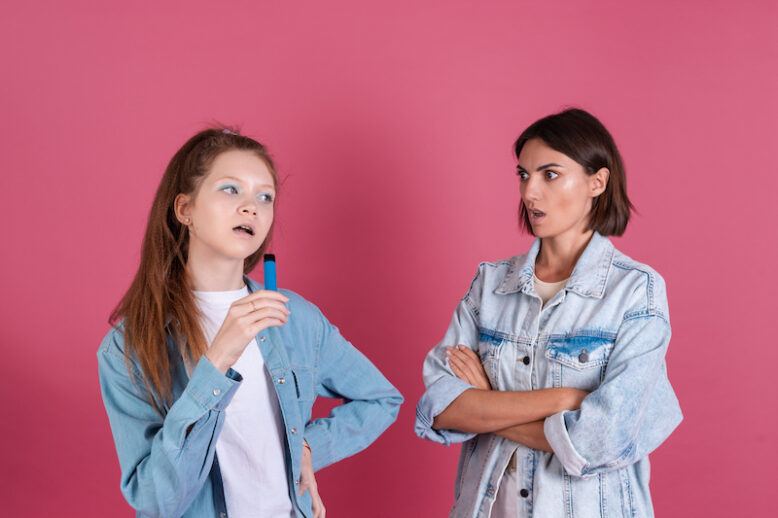 Modern mom and daughter in denim jackets on terracotta background