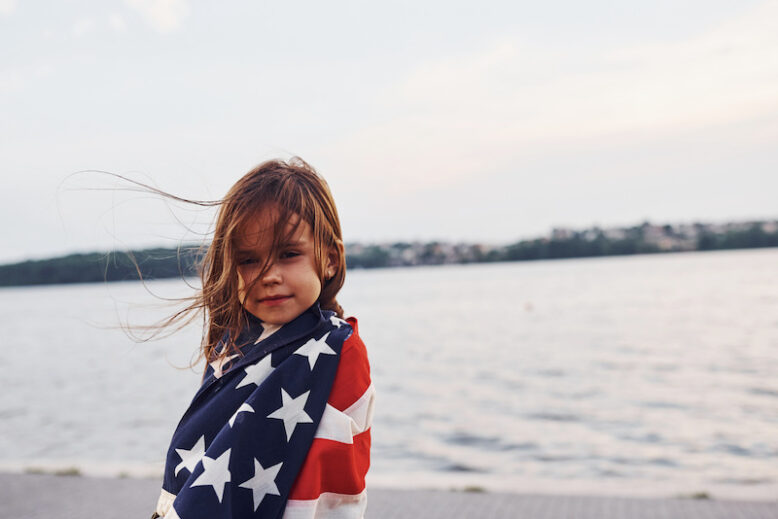 Patriotic female kid with American Flag in hands