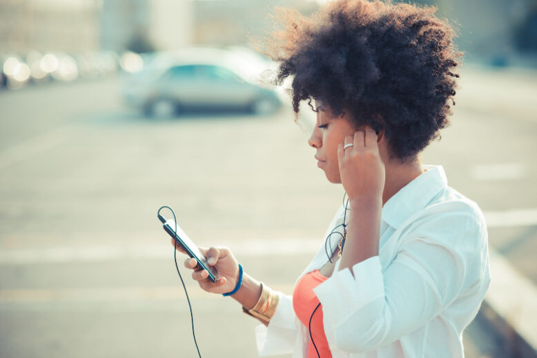 Woman listens to music in headphones on the street.