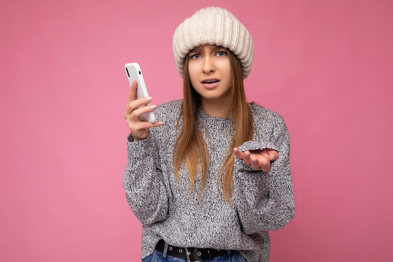 Young blonde woman using mobile phone and don't understanding.