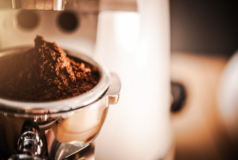 Close Up Of Barista Espresso Machine Grinding Fresh Batch Of Coffee Beans.