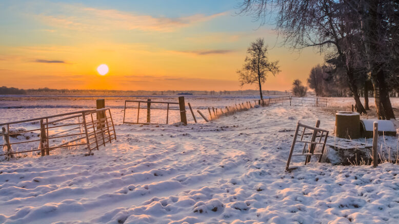 Rising sun over Winter Landscape with Snowy Fields and Blue Sky in Drenthe Netherlands