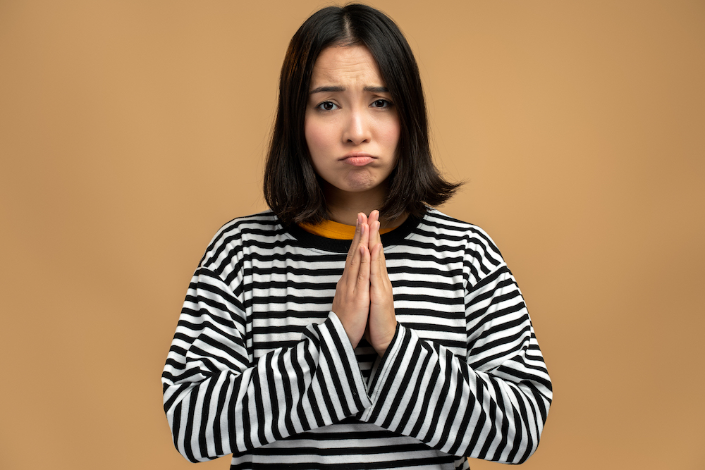 Please, I'm begging forgive. Portrait of upset worried woman looking with imploring desperate grimace and praying for help, asking apology. Studio shot isolated on beige background