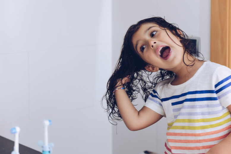 little girl playing with wet hair in front of the mirror after taking a bath