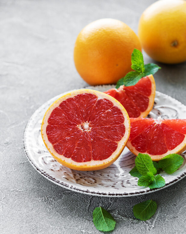 Plate with grapefruits on a concrete background