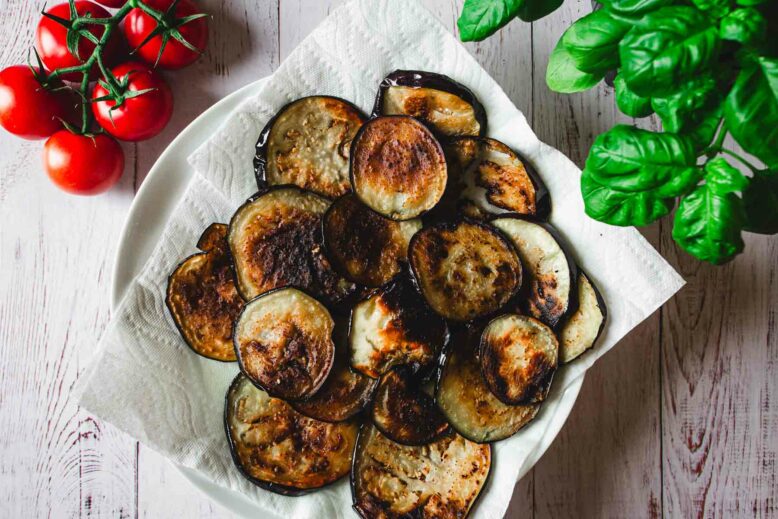 Fried eggplant slices with basil plant and tomates