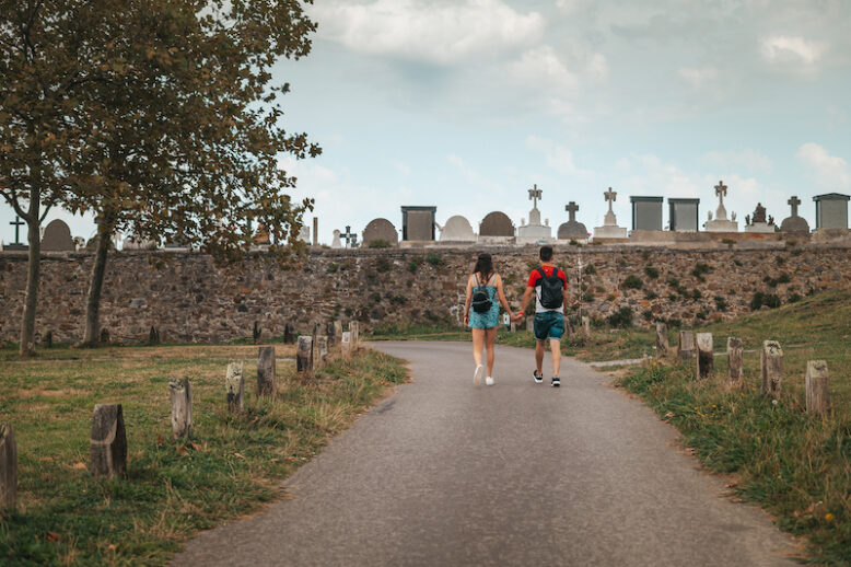 Couple walking by a path near a cemetery in Europe.