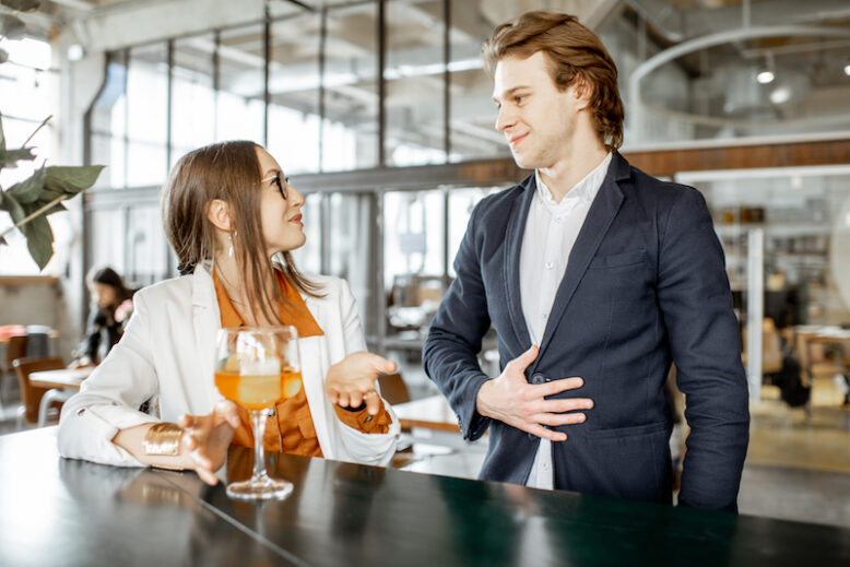 Businessman flirting with young woman sitting with cocktail at the bar