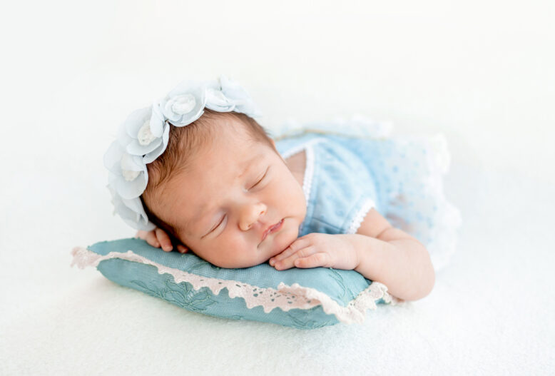 Adorable newborn baby girl sleeping on pillow closeup portrait.