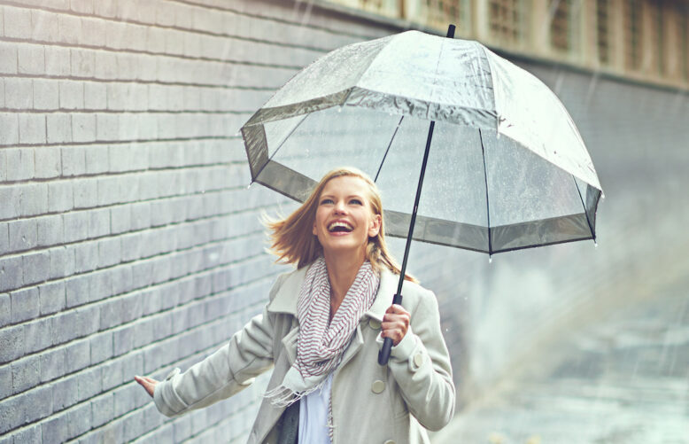 Full length shot of an attractive young woman playing in the rain.