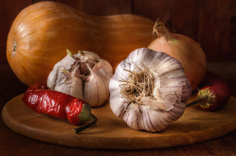 garlic and other vegetables on a dark wooden background
