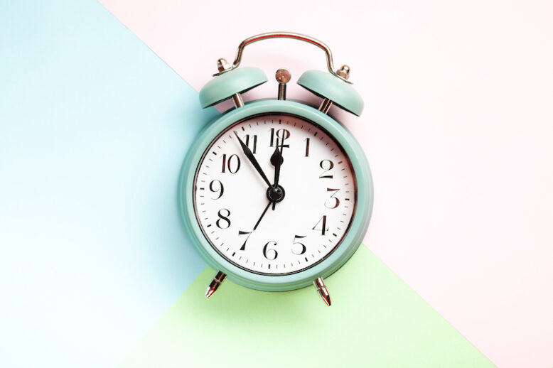 Retro style alarm clock over the pastel blue, pink and green background