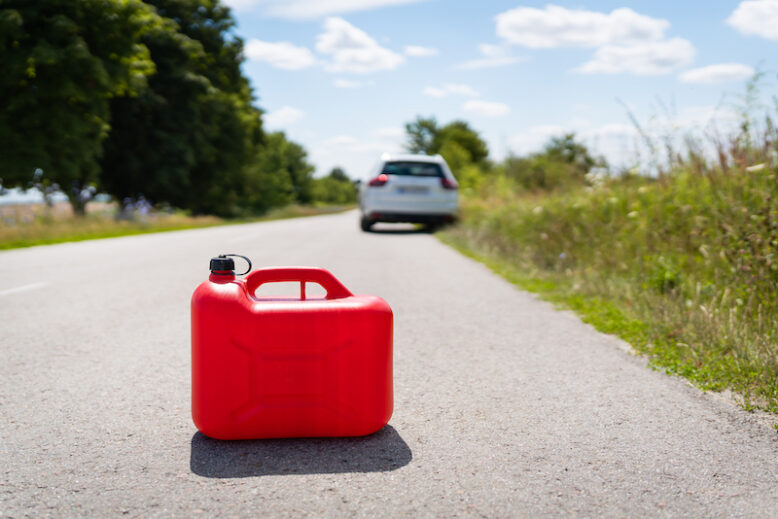 A car parked on the side of the road, an empty red canister.