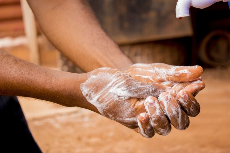 A hand of a male washing his hands with water and soap