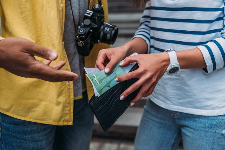 Cropped view of woman checking money in wallet near a friend