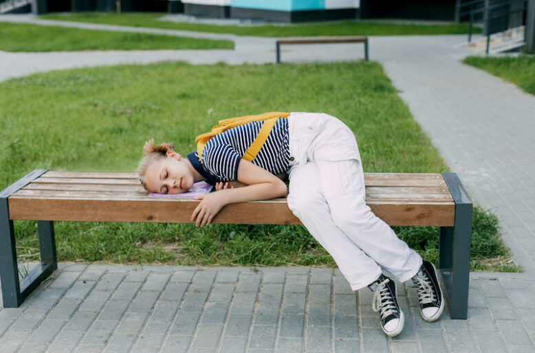 Schoolgirl is tired at school and lying on the bench.