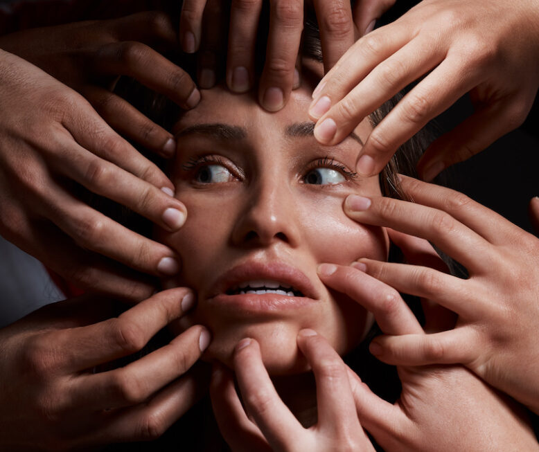 Shot of hands grabbing a young womans against a dark background