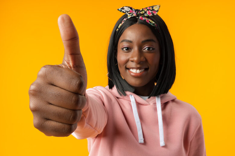 African young woman over isolated yellow background with thumbs up gesture