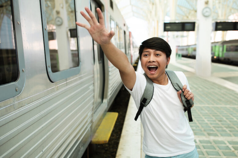 Stressed young traveller running by train station platform.