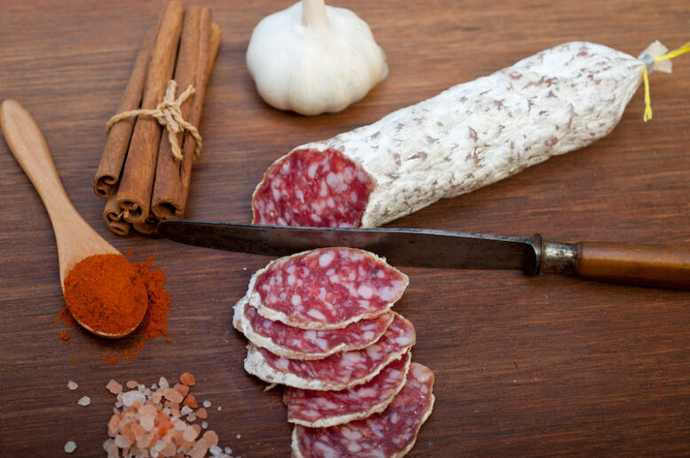 traditional Italian salame cured sausage sliced on a wood board