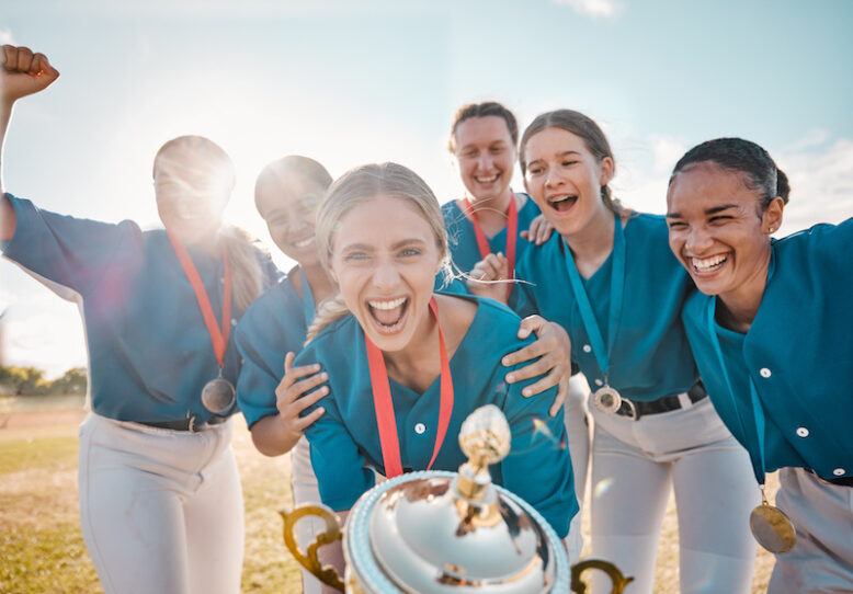 Winning trophy and team of women in baseball portrait with success, achievement and excited on fiel.