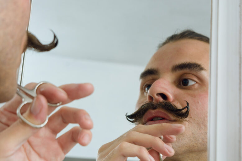 young person trimming his moustache in the bathroom