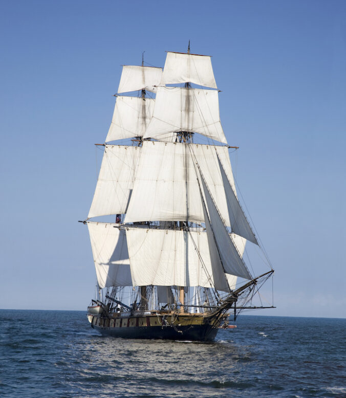 A tall ship known as a brigantine sails on blue water