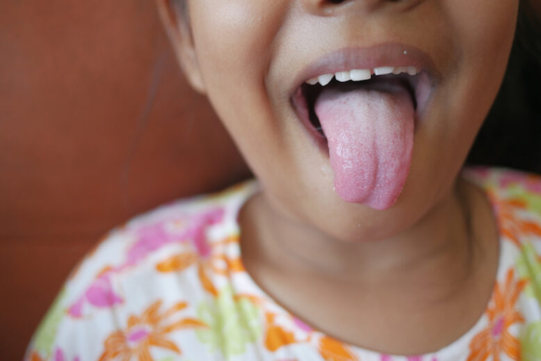 child shows his tongue closeup .