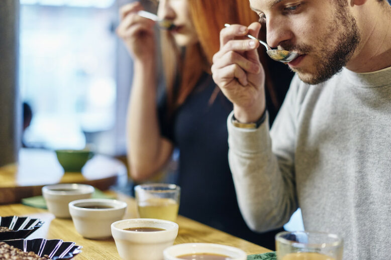 Man and woman tasting bowls of coffee at coffee shop tasting