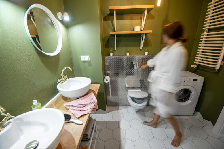 Beautiful loft interior bathroom with motion blurred woman in bathrobe draining water in the bowl