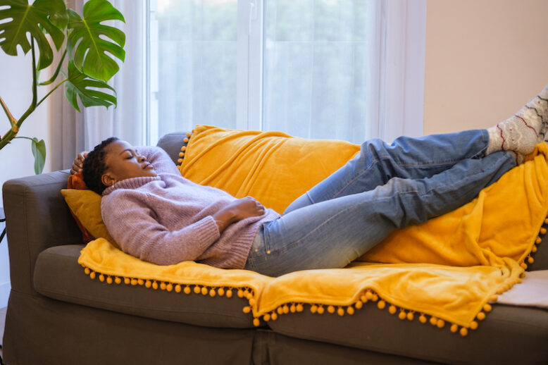 Young woman napping on the sofa in her living room.