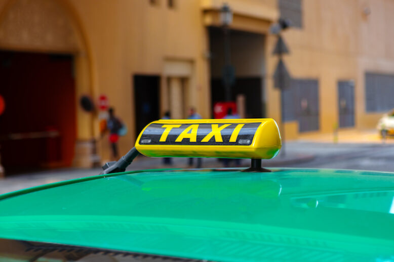 Taxi sign on the roof of a car in a street, close up