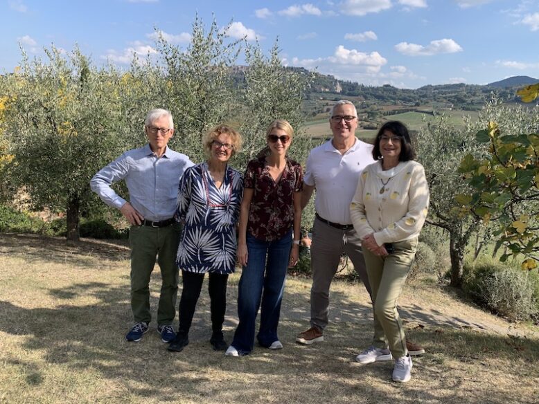 five guests standing in front of tuscan landscape