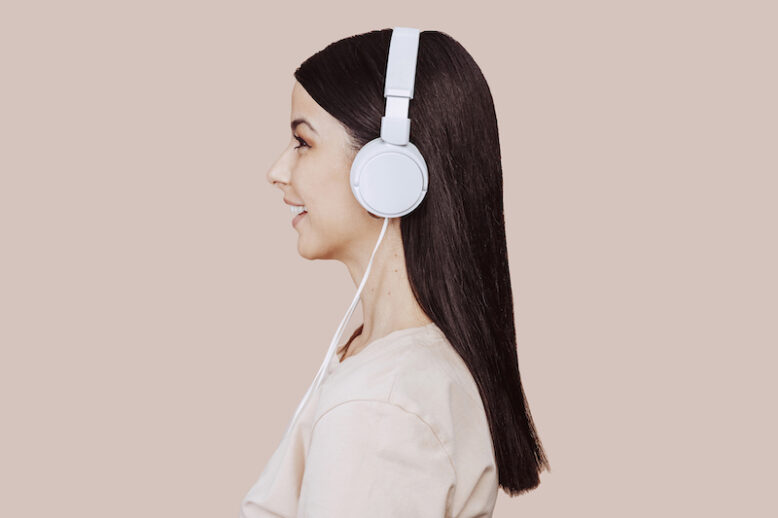 girl in beige shirt listening music with headphones