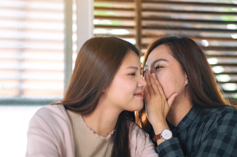 Two female friends telling and gossiping