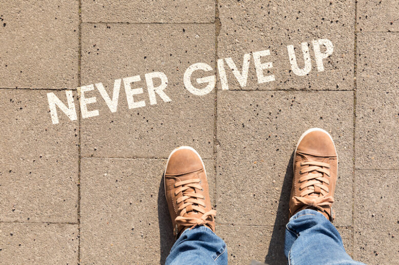 shoes on asphalt with text never give up